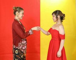 Two Asian woman traditional kebaya and modern dress red yellow paper background meet great photo