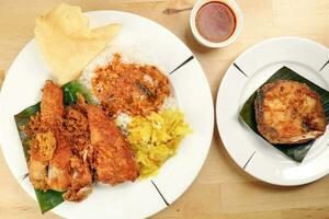 Traditional Malaysian Indian food white rice cabbage vegetable meat deep fried chopped chicken leg topped up with spicy mix gravy wood table background photo