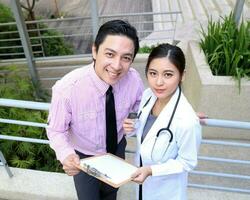 South East Asian young Malay Chinese man woman medical doctor talking discussing outdoor photo