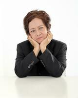 Elderly asian Chinese female on white background wearing black suit thinking hand on cheek look down photo