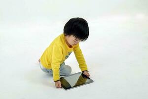 South East Asian young boy child playing tablet tab computer pc on white background photo