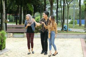 Young Asian Malay man woman outdoor green park walk talk discuss mingle happy laugh photo