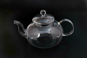 Empty transparent glass see through teapot kettle on black background photo