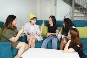 Young Asian woman group talk gossip chat sing drink cheers party fun enjoy emotion on blue living room sofa photo