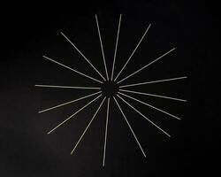 Dry raw Spaghetti laid on black background sunray glow pattern concept photo