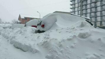 carros coberto de neve depois de uma neve nevasca. residencial construção dentro a fundo video