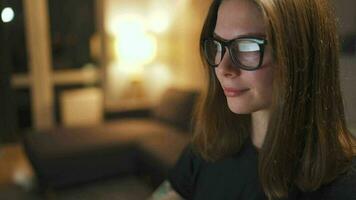 Woman in glasses looking on the monitor and surfing Internet at night. The monitor screen is reflected in the glasses. Work at night. Home Office. Remote work video