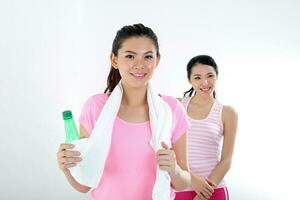 Two beautiful young south east Asian Chinese woman exercise workout yoga drink bottle stretch on white background photo