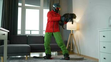 divertido video. hombre vestido como un snowboarder paseos un tabla de snowboard en un alfombra en un acogedor habitación video