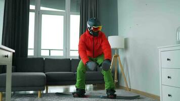 roligt video. man klädd som en snowboardåkare rider en snowboard på en matta i en mysigt rum video