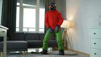 divertido video. hombre vestido como un snowboarder paseos un tabla de snowboard en un alfombra en un acogedor habitación video