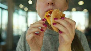 mujer comiendo hamburguesa y papas fritas en un café de cerca. hamburguesa en hembra manos video