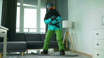 divertimento video. uomo vestito come un' snowboarder cavalcate un' Snowboard su un' tappeto nel un' accogliente camera video