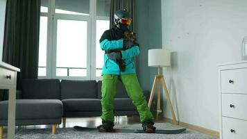 Fun video. Man dressed as a snowboarder rides a snowboard on a carpet in a cozy room video