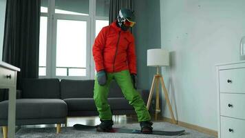 Diversão vídeo. homem vestido Como uma snowboarder passeios uma snowboard em uma tapete dentro uma acolhedor quarto video