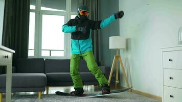 Diversão vídeo. homem vestido Como uma snowboarder passeios uma snowboard em uma tapete dentro uma acolhedor quarto video