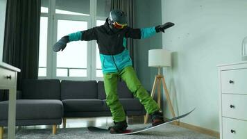 divertido video. hombre vestido como un snowboarder paseos un tabla de snowboard en un alfombra en un acogedor habitación video