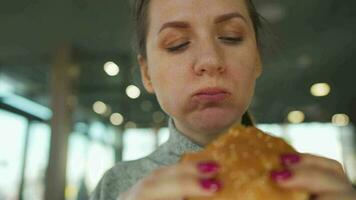 kvinna äter hamburgare och frites i en Kafé närbild. burger i kvinna händer video