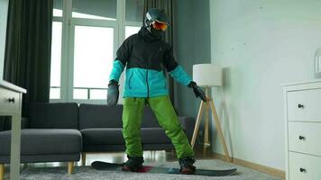 Fun video. Man dressed as a snowboarder rides a snowboard on a carpet in a cozy room video