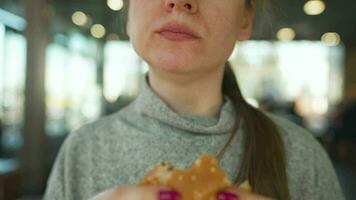 Woman eating hamburger and fries in a cafe close-up. Burger in female hands video