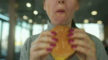 mulher comendo Hamburger e fritas dentro uma cafeteria fechar-se. hamburguer dentro fêmea mãos video
