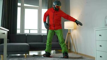 divertido video. hombre vestido como un snowboarder paseos un tabla de snowboard en un alfombra en un acogedor habitación video