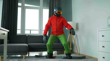 Diversão vídeo. homem vestido Como uma snowboarder passeios uma snowboard em uma tapete dentro uma acolhedor quarto video