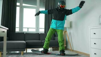 divertido video. hombre vestido como un snowboarder paseos un tabla de snowboard en un alfombra en un acogedor habitación video