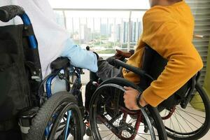 Portrait of young man woman south east Asian malay sitting on wheelchair look outside over balcony window. Paralyzed waist down. photo