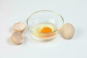 Raw Egg Yolk and white liquid in transparent glass bowl eggshell white background photo