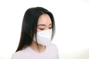 Beautiful young south east Asian woman wearing N95 anti virus bacterial surgical face mask on white background side view look down photo