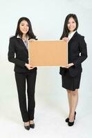 Two young asian malaysian business office woman holding blank copy text space sign board on white background photo