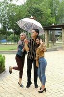 Young Asian Malay man woman outdoor green park walk talk discuss mingle under umbrella photo