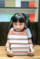 girl child resting head on stack of book look at camera photo