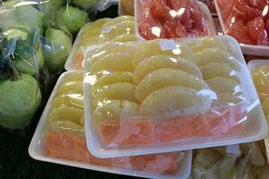 Fresh cut fruit wrapped in plastic selling at street market pomelo mango durian mango jackfruit photo