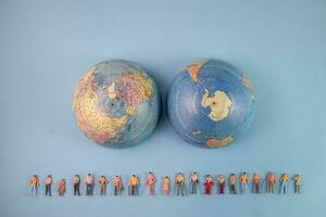 Miniature human figure figurine male female doll row line world map globe border copy text sign space on blue paper background photo