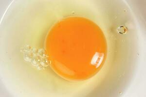 Raw Egg Yolk and white liquid in transparent glass bowl white background photo