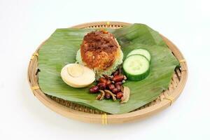 Nasi Lemak fragrant rice cooked in coconut milk served with sambal friend peanut anchovy boiled egg packed in banana leaf on round bamboo plate on white background photo