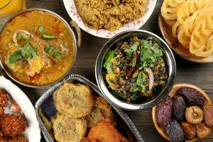 Bengali Iftar Ramadan breakfast spread ripe dates peep fried spicy piaju onion fitter eggplant tanpura potato chop haleem jilapi khichuri rice chana sola curry on rustic wooden table photo