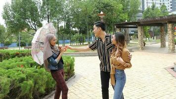 Young Asian Malay man woman outdoor green park walk talk discuss mingle under umbrella photo