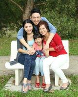 Southeast Asian multigeneration family parents daughter grandmother father mother child pose happy sit stand  outdoor park photo