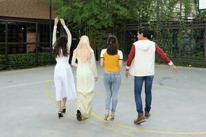 Group young asian chinese malay man woman wearing headscarf outdoor walk talk discus friend student colleague happy exited form back photo