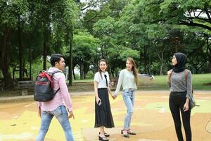 joven asiático malayo chino hombre mujer al aire libre parque caminar estar estudiar hablar discutir punto ordenador portátil archivo libro mochila foto