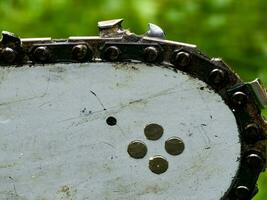 Sharpened sharp teeth of an electric saw chain on a blurred green background. photo