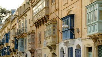 Exterior of typical houses on the Mediterranean island of Malta. Typical residential houses in the cities in Malta, multiple floors and colorful wooden balconies and beautiful limestone buildings. photo