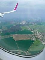 View from the airplane window. Beautiful view of green agricultural field and village. Wonderful panorama seen through window of an plane. Traveling by air concept photo