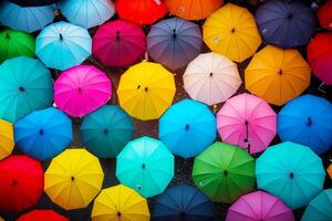 Group of multicolored umbrellas sitting on the ground in crowd of people. photo