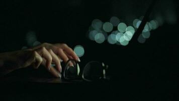 Accelerated video of female hands is typing on a laptop at night. Blurred lights on the background. Quick motion