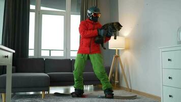 divertido video. hombre vestido como un snowboarder paseos un tabla de snowboard en un alfombra en un acogedor habitación video