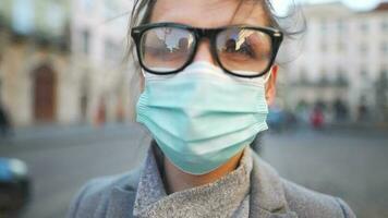pandemia proteção do a covid-19 coronavírus. retrato do uma mulher dentro uma casaco, óculos e uma protetora médico mascarar. óculos névoa acima a partir de respiração video
